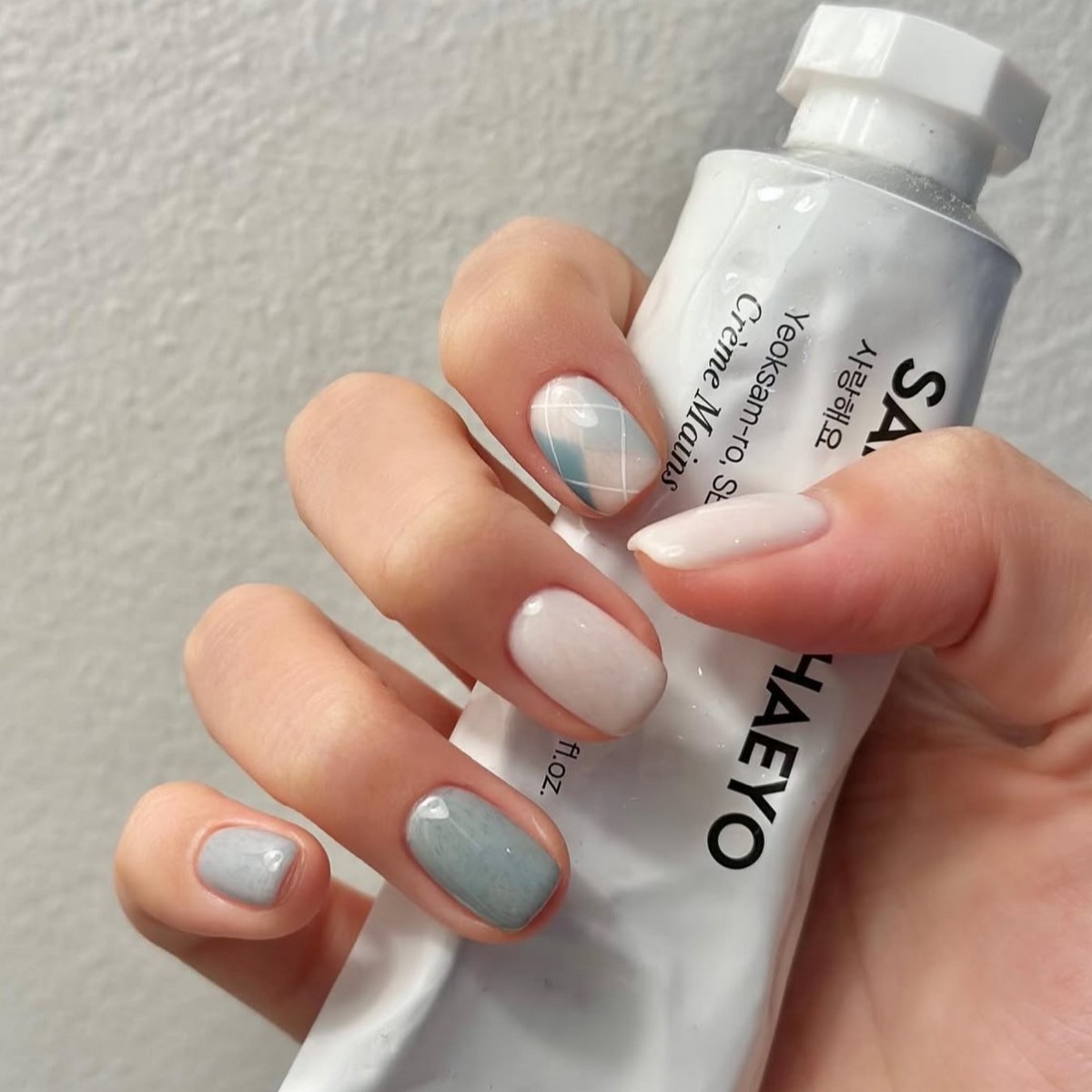 Маникюр на короткие ногти в пастельно-молочной гамме с клетчатым принтом на одном пальце