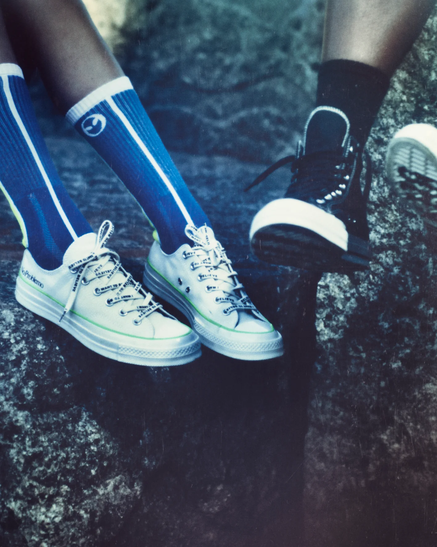 Белые низкие и черные высокие Chuck 70 No Problemo x Converse на ногах среди камней